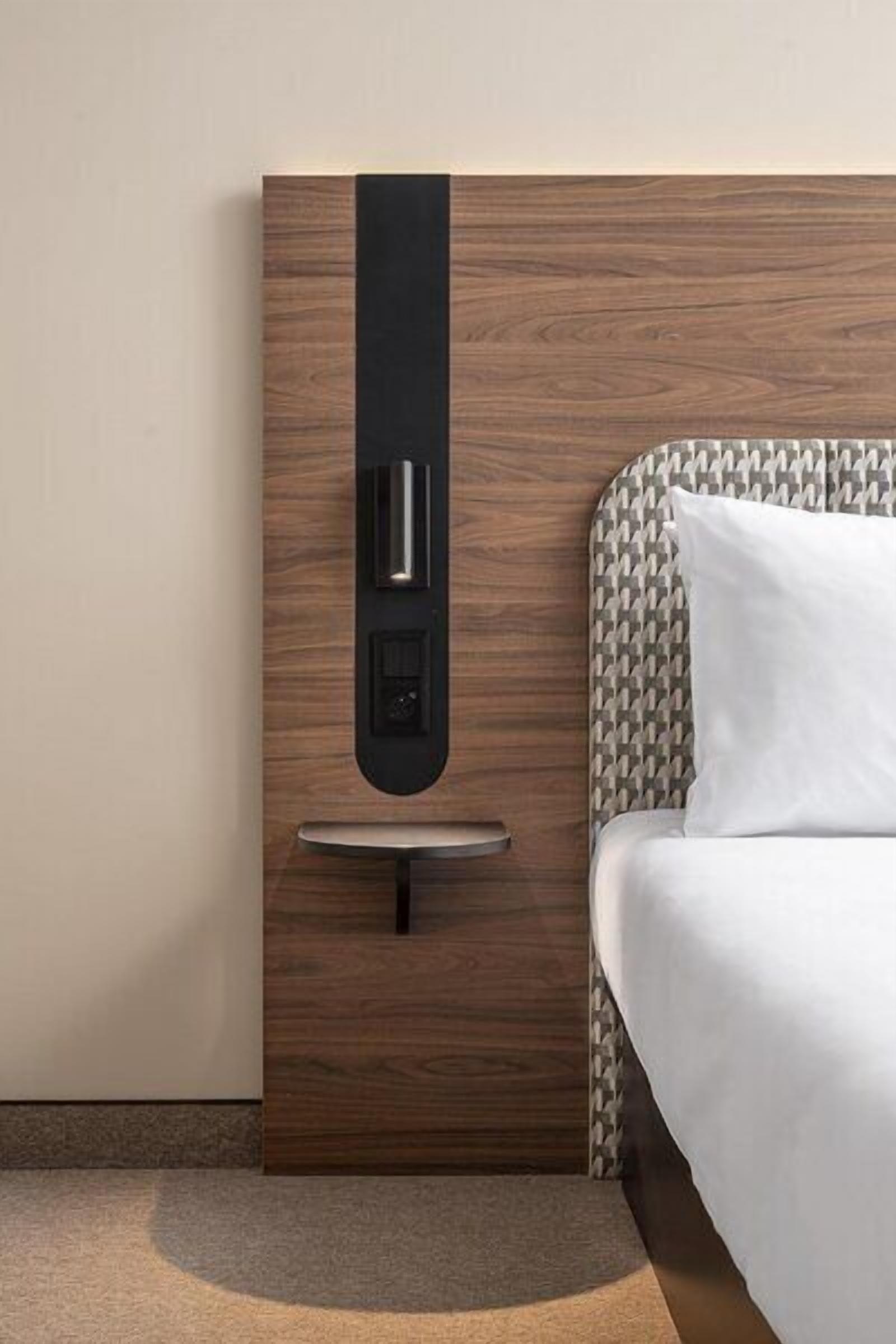 Una habitación de hotel moderna con cabecera de madera, mesita de noche y cafetera integrada.