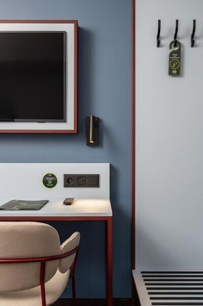 Une chambre comprenant un lit, une table de chevet, une chaise, un téléviseur et un radiateur fixé au mur.
