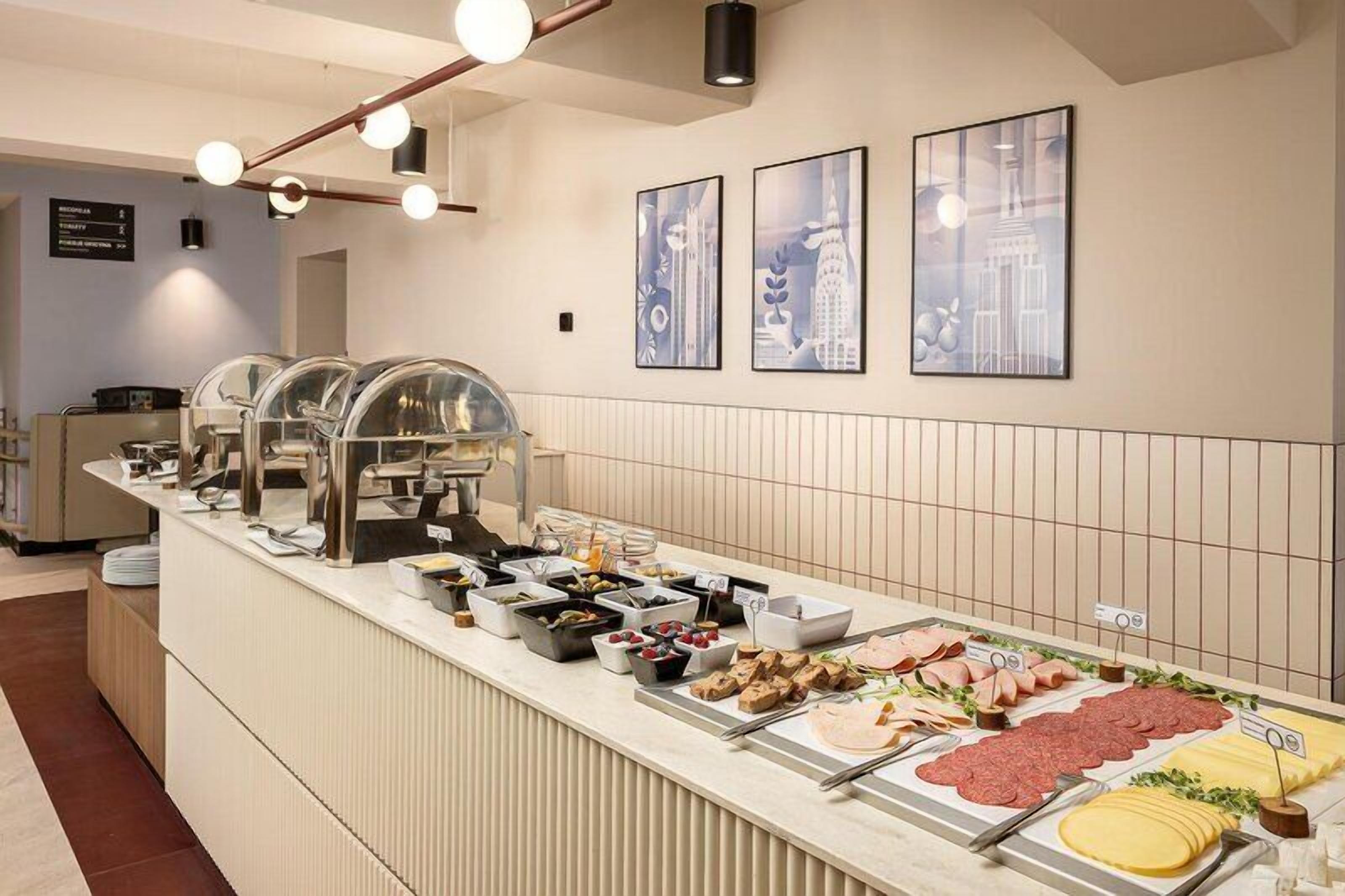 A buffet with various food items, a counter with a menu, and framed pictures on the wall.