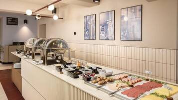 A buffet with various food items, a counter with a menu, and framed pictures on the wall.