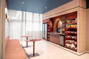 A B&B shop with a seating area, a counter with beverages, and a display of snacks. - B&B HOTEL Wrocław Old Town (Wrocław)