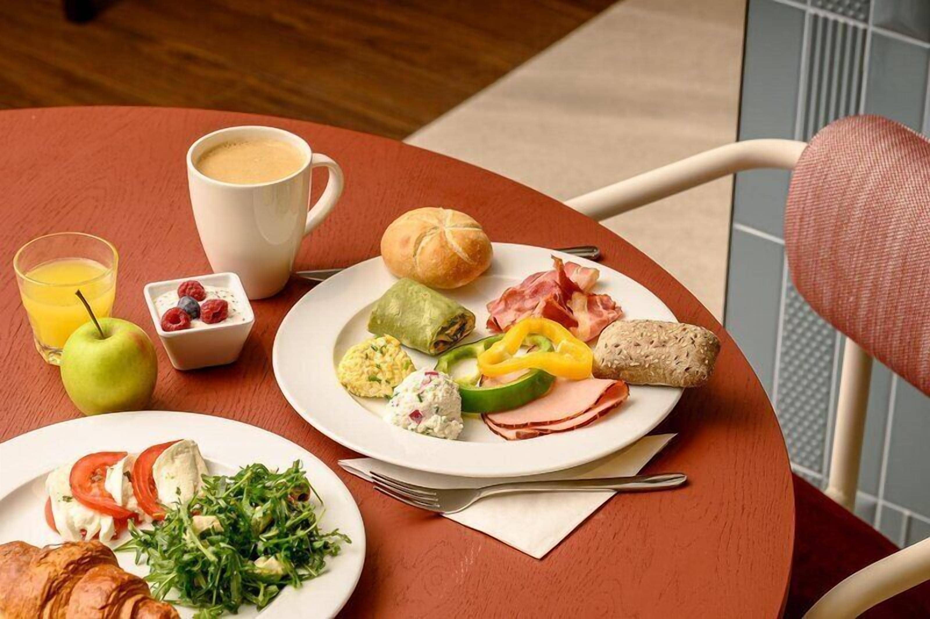Ein Frühstückstisch mit Speisen, einer Kaffeetasse, einem Glas Orangensaft und einem Croissant.