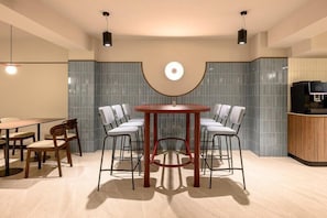Un interior moderno con una mesa redonda rodeada de sillas, una zona de bar y un televisor.
