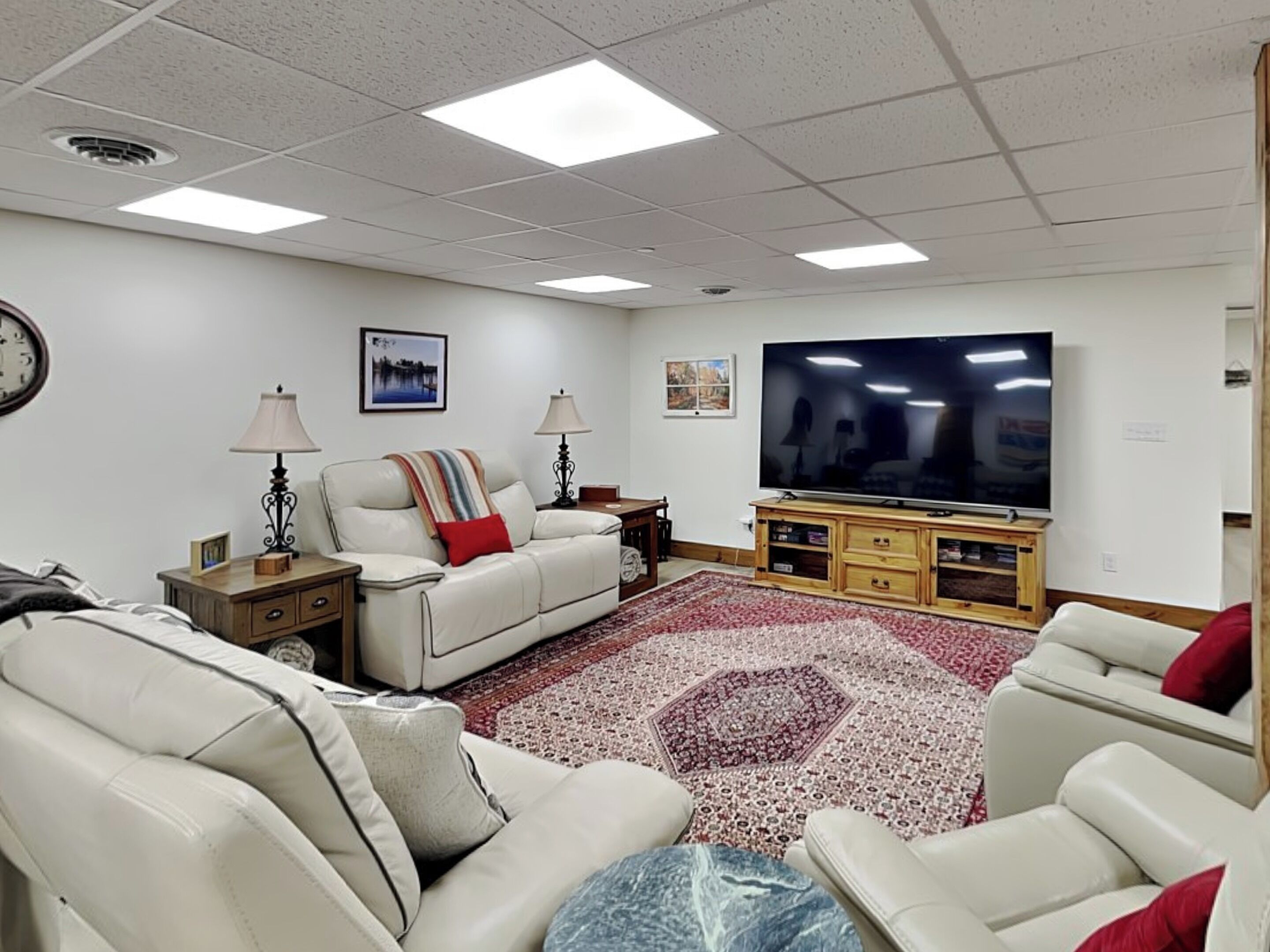 A living room with a sofa, two side tables, a flat-screen TV, and a patterned rug.
