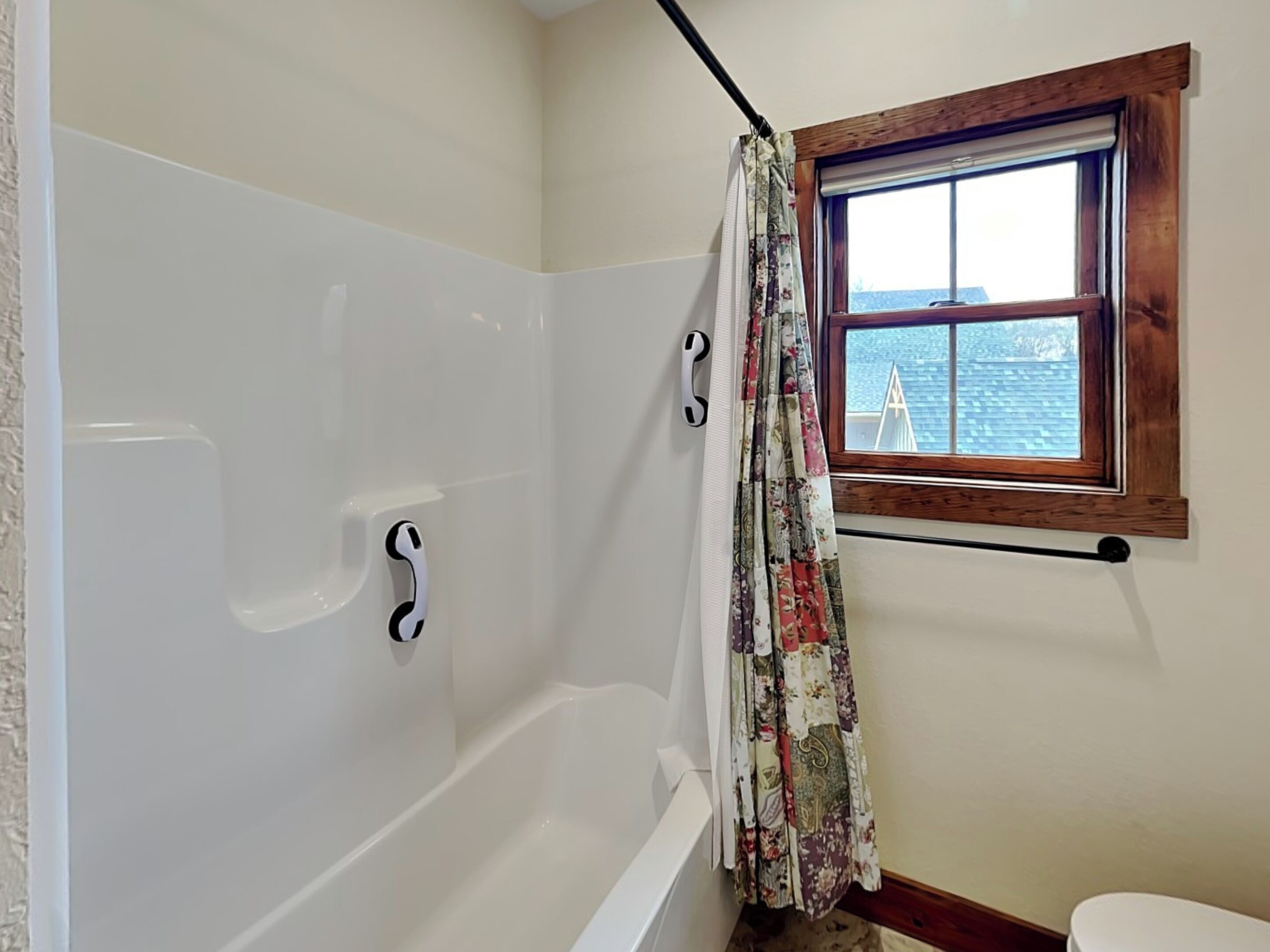 A bathroom with a white bathtub, a wooden window, and a curtain.
