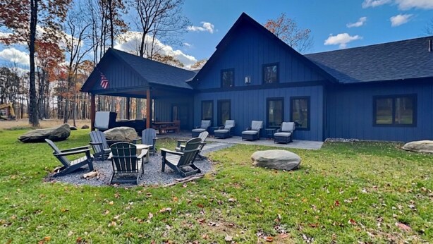 A blue house with a patio area, outdoor seating, and a flag. - Mountain Whisper (McHenry)