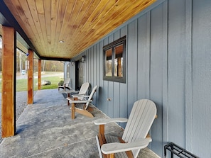 A covered porch with Adirondack chairs, a concrete floor, and a wooden ceiling. - Mountain Whisper (McHenry)