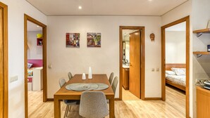 A dining area with a wooden table, chairs, and two wall-mounted bicycle posters. - Apartment 'Villa Rocío' with Sea Views, Shared Pool and Wi-Fi (Calella de Palafrugell)