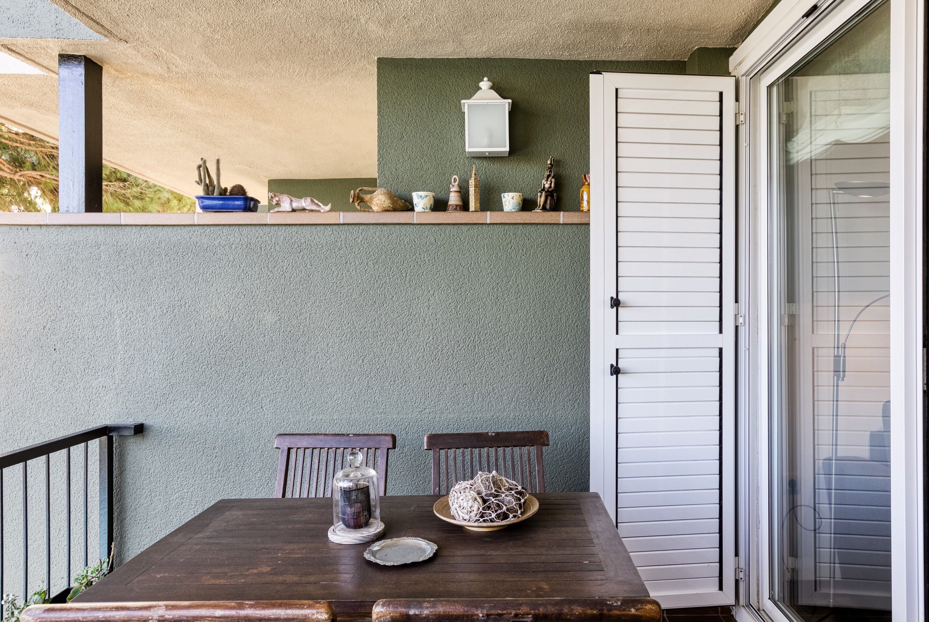 Et spiseområde med et bord, stole, en glaskuppel, en keramiktallerkener og en dekorativ genstand på væggen.