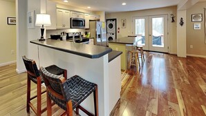 Una cocina moderna con una isla central, sillas de madera y un comedor con taburetes.
