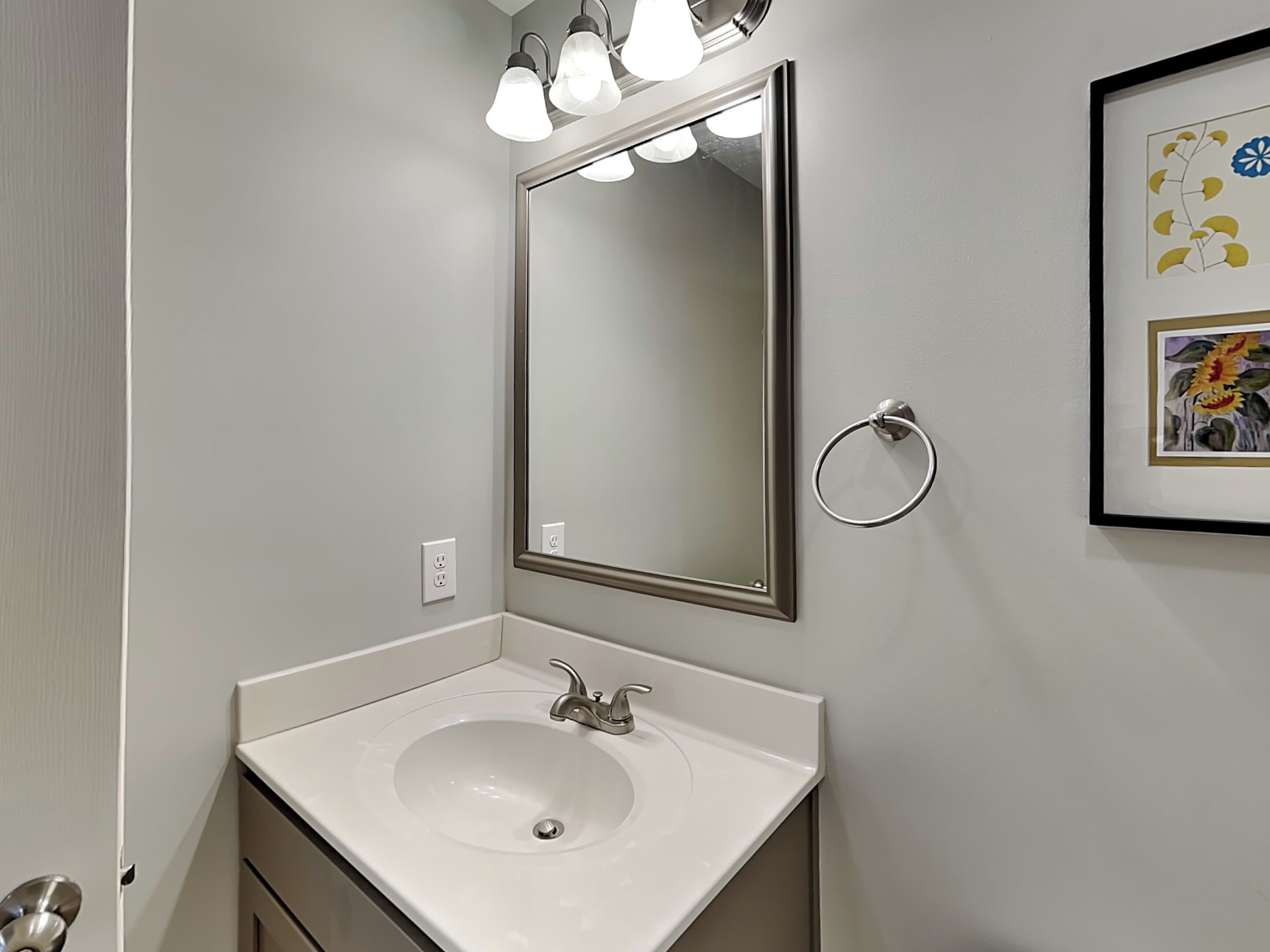 A bathroom with a white sink, a mirror, and a towel ring.