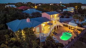 A multi-story house with a large deck, a swimming pool, and a hot tub.