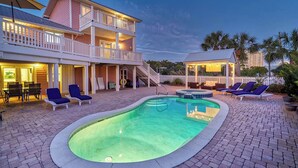 A two-story building with a swimming pool, lounge chairs, and a covered area.