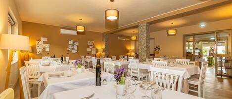 A restaurant with multiple tables set for dining, featuring white tablecloths, neatly arranged cutlery, and decorative centerpieces.