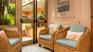 A wicker chair with striped cushions and a wall-mounted sign reading "HOTEL DONATELLA 38 YEARS TOGETHER". - hotel ristorante Donatella (Posada)