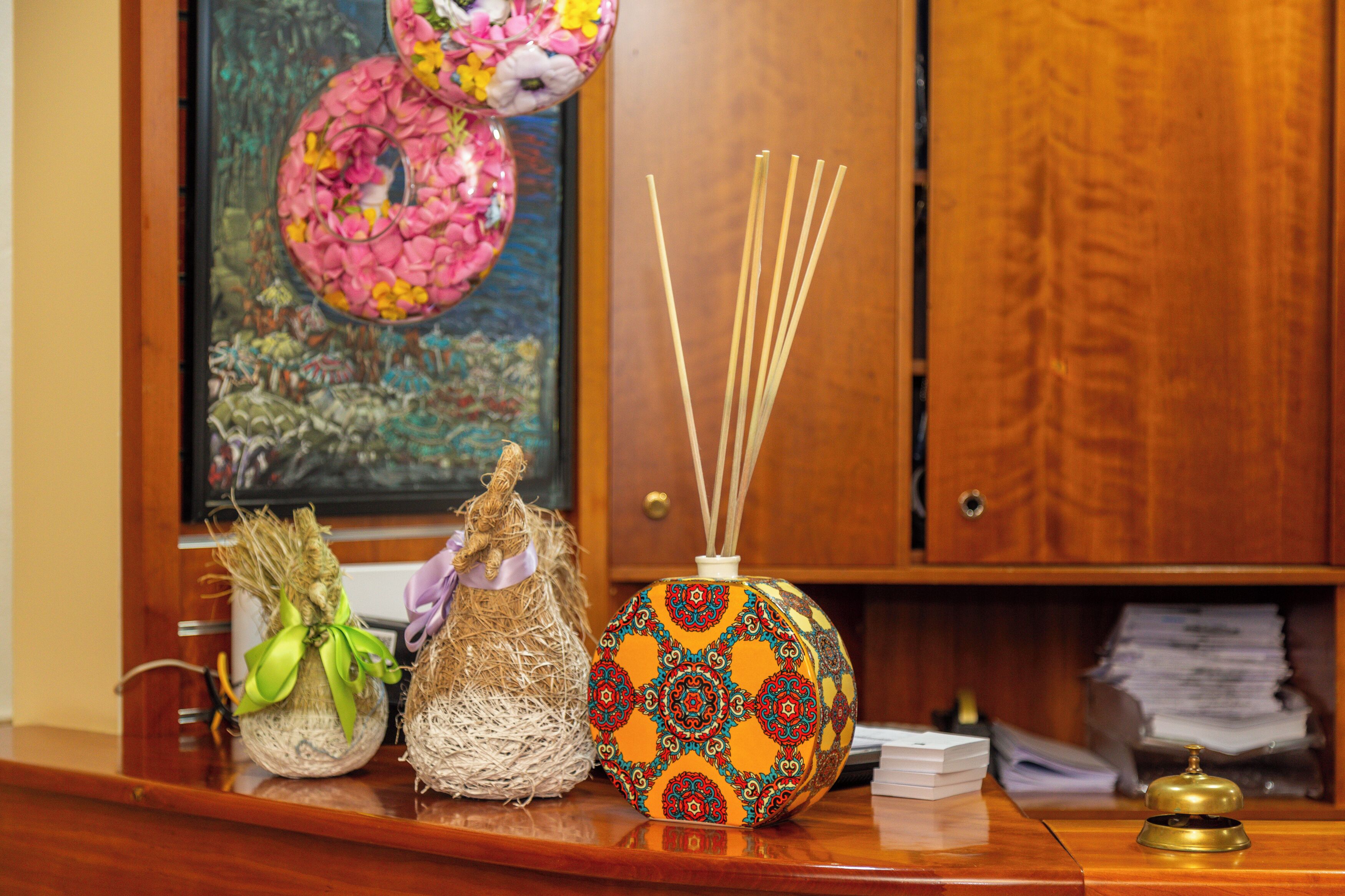 A wooden desk with a decorative vase, a small plant, and a stack of papers.
