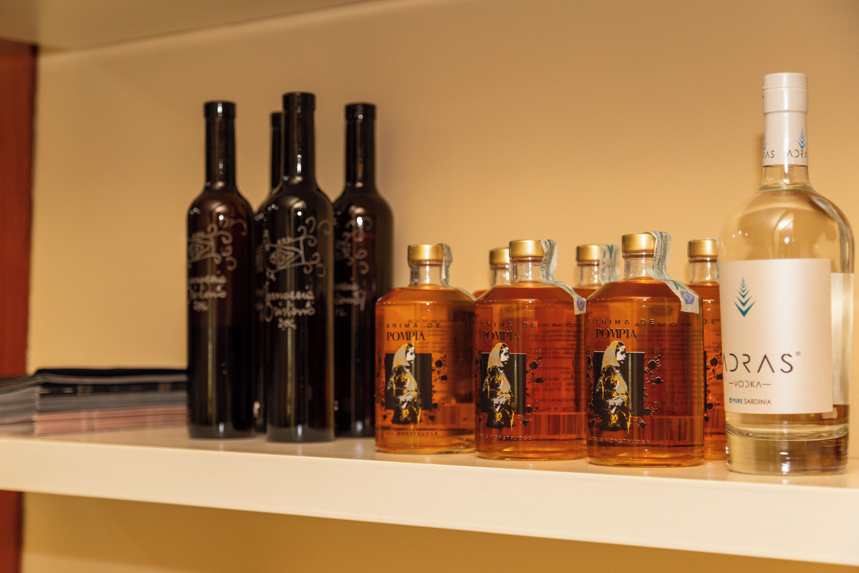 A shelf with various bottles of alcohol, including a prominent bottle labeled "DRAS Vodka."