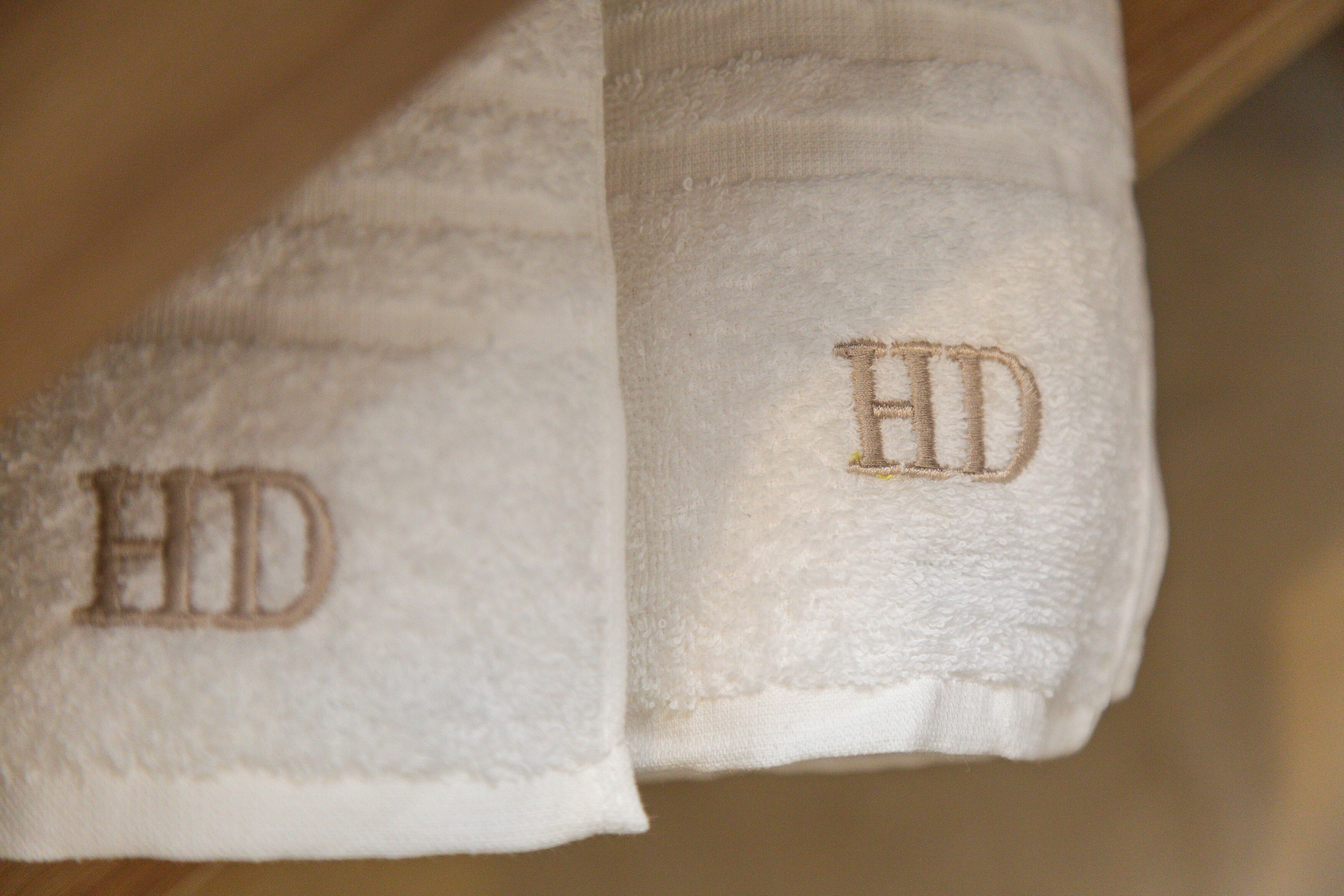Uma toalha branca com bordado as letras "HD".