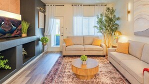 Un salon avec un canapé, une table basse, un téléviseur et une cheminée.