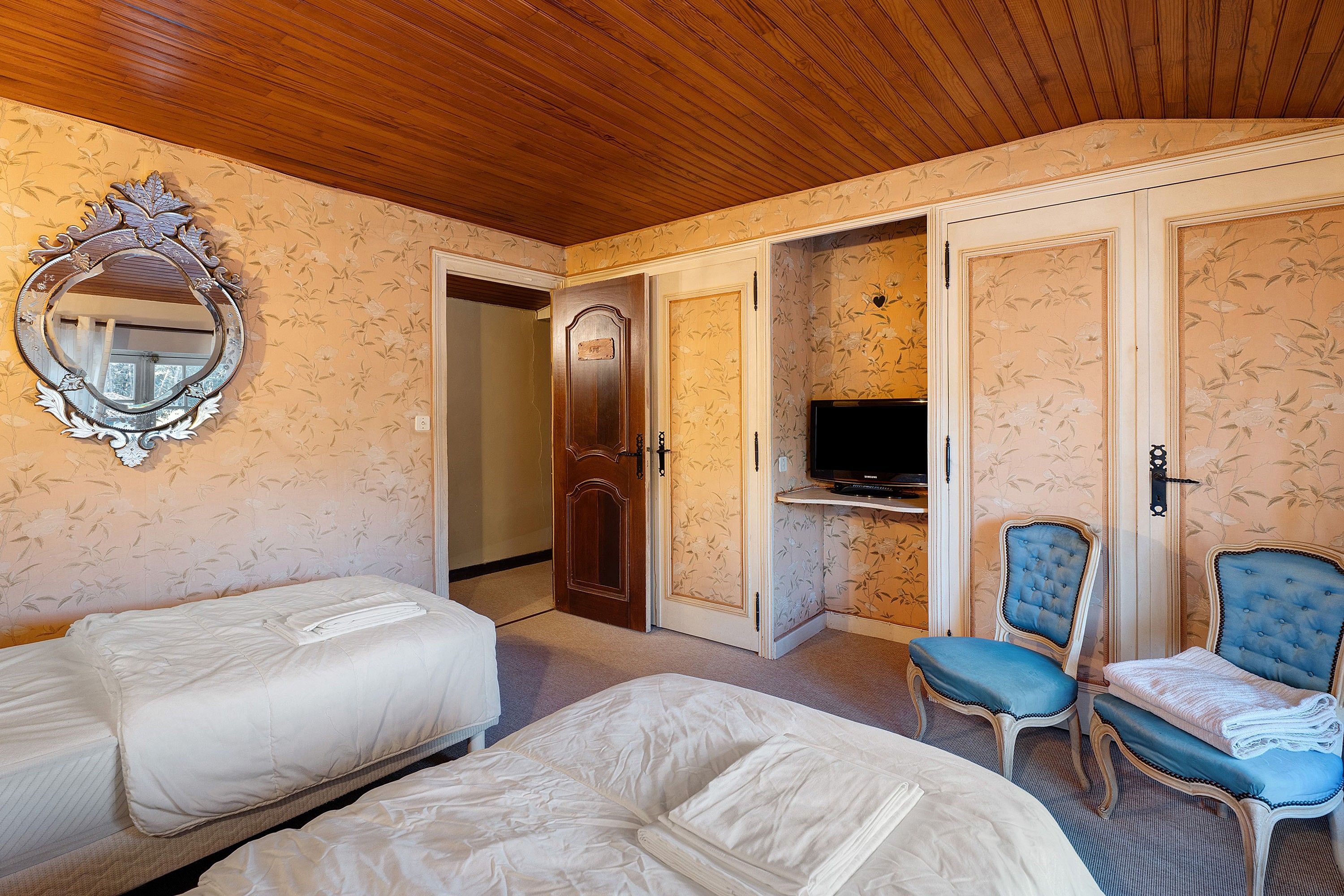 Habitación de hotel con dos camas, televisor y una zona de estar con dos sillones.