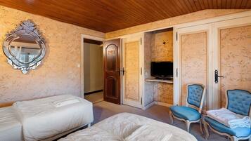 Habitación de hotel con dos camas, televisor y una zona de estar con dos sillones.
