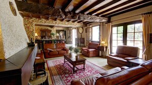 A traditional living room with leather sofas, a wooden coffee table, and a patterned rug. - Gîte des roties: Restored Family Home with Pool in a 7-Hectare Park (Poncins)