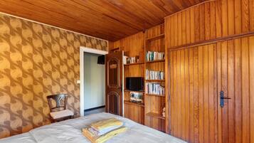 A room with a bed, wooden wardrobe, and bookshelves.