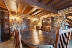 Un comedor con una mesa y sillas de madera, rodeado de un papel tapiz floral y muebles de madera.