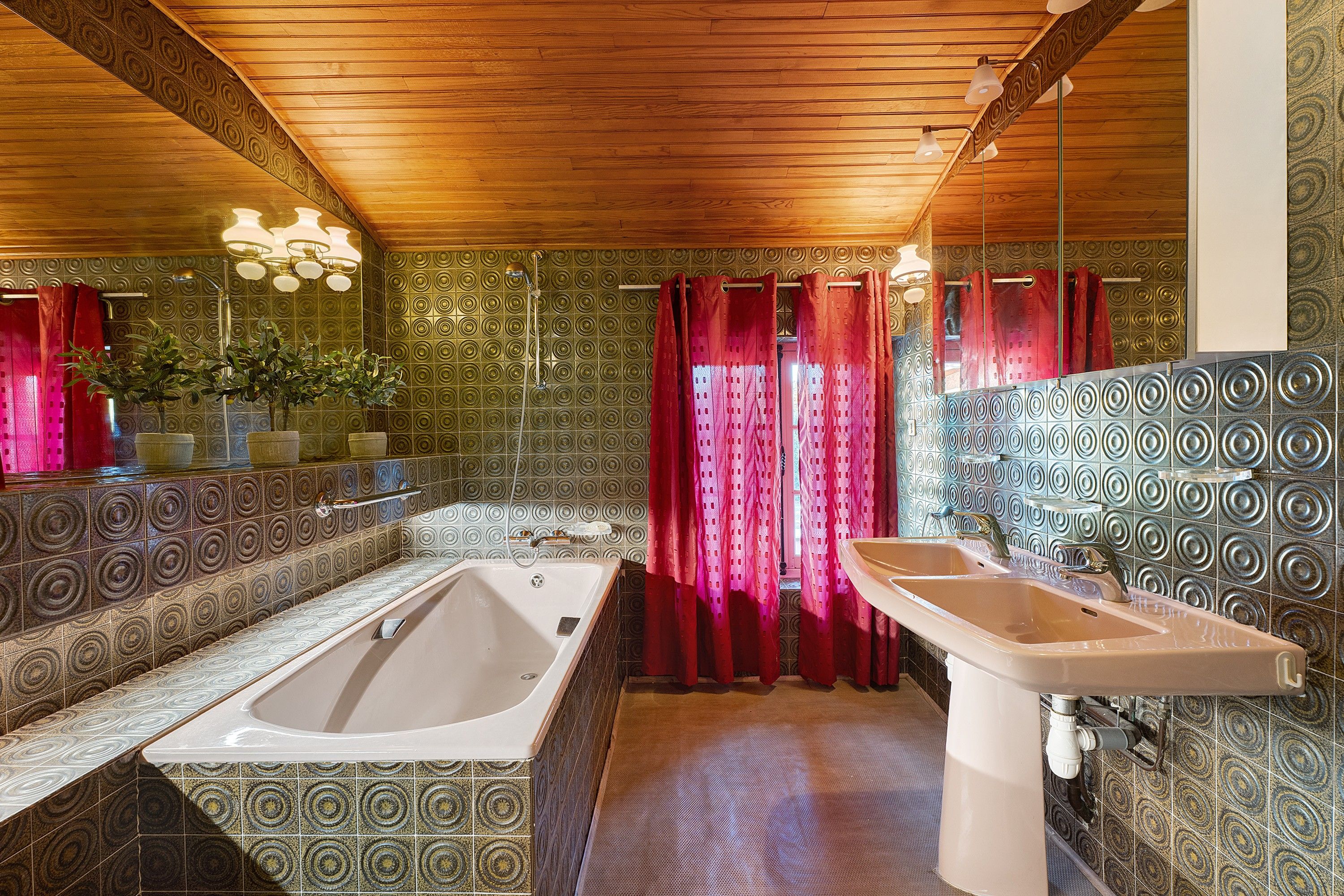 A bathroom with a large bathtub, a sink, and patterned walls.