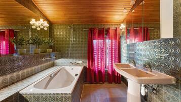 A bathroom with a large bathtub, a sink, and patterned walls.