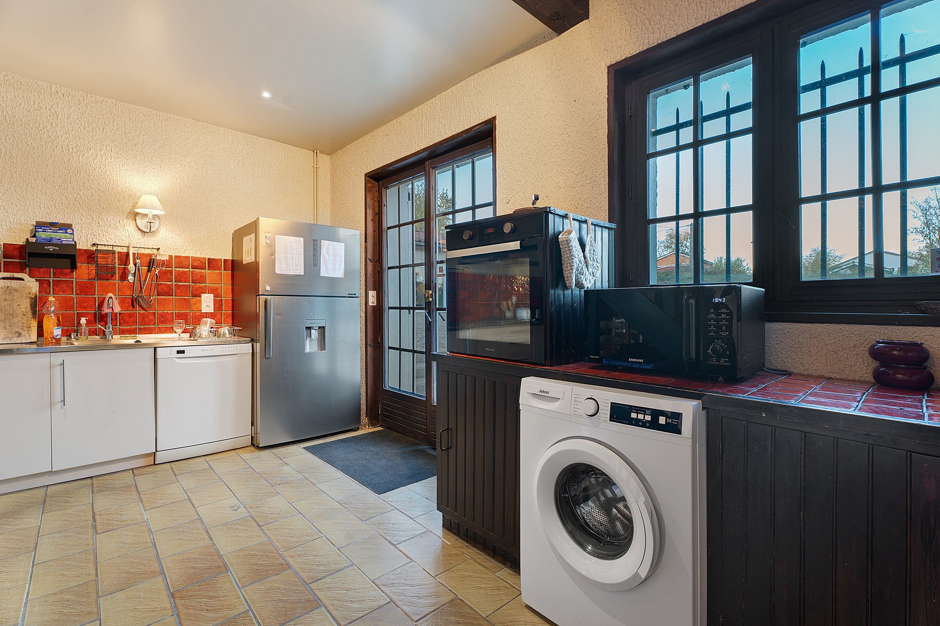 Een keuken met een wasmachine, oven en magnetron.