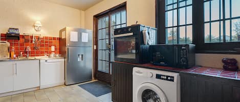 A kitchen with a washing machine, oven, and microwave.