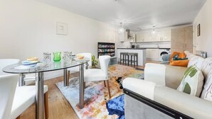 A modern living room with a glass dining table, white sofas, and a colorful rug. - *Modern Spacious 1 Bedroom Flat in Camden* (London)