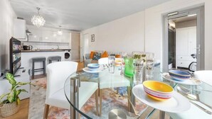 A modern kitchen with white cabinets, a glass dining table, and a chandelier. - *Modern Spacious 1 Bedroom Flat in Camden* (London)