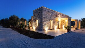A modern stone building with a flat roof, large windows, and a covered patio area. - Exclusive villa with pool among aromas, colors and centuries-old olive trees of Salento (Spongano)