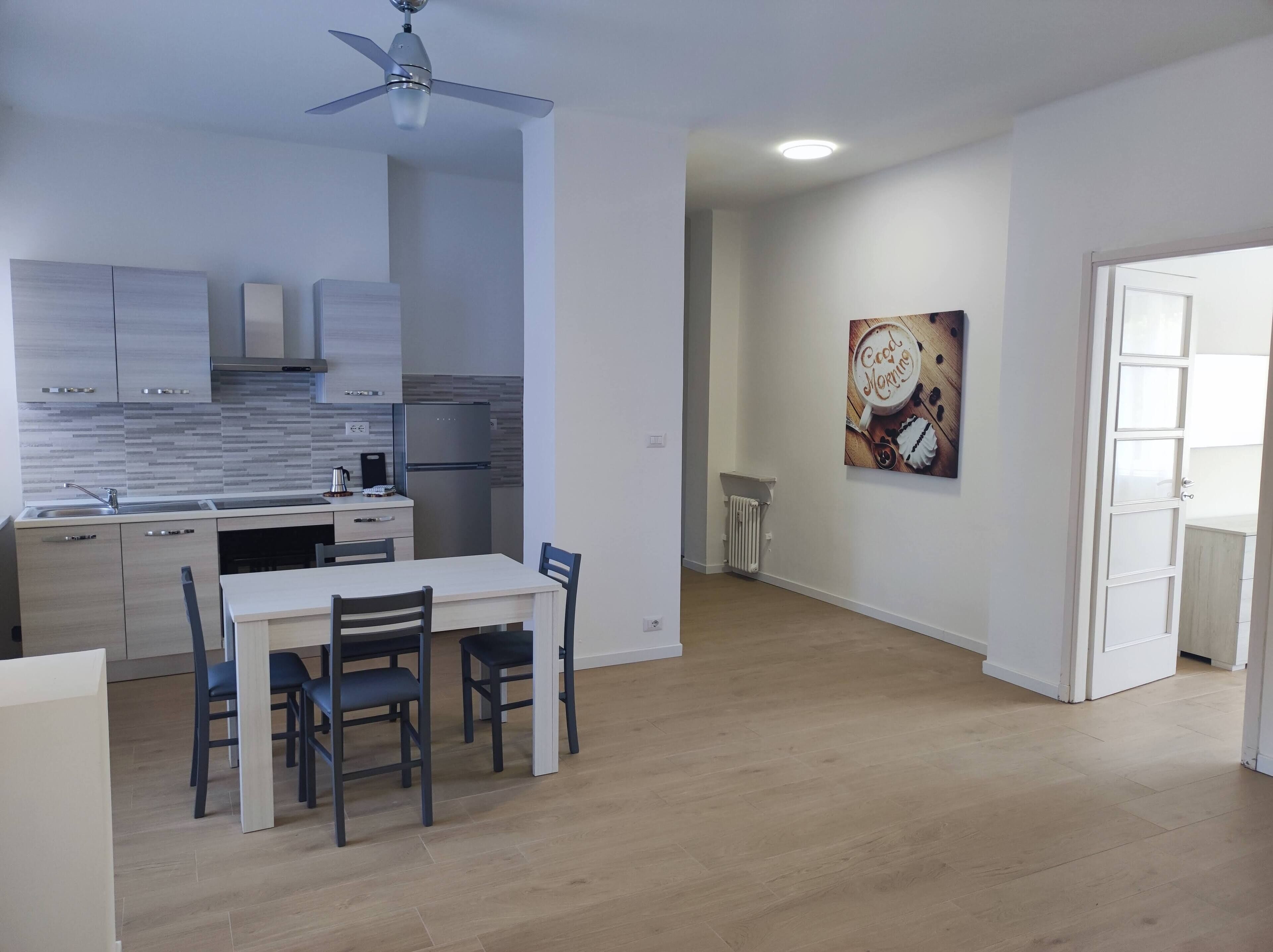 A modern kitchen with a dining area, a ceiling fan, and a wall-mounted artwork.