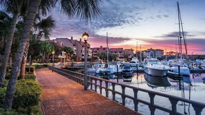 A marina with boats docked, a waterfront walkway, and buildings in the background. - Fairway View Getaway in Palmetto Dunes (Hilton Head Island)