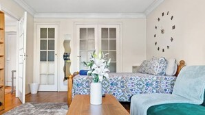 A cozy room with a bed, a wooden table with a vase, and a clock on the wall. - *Modern Spacious studio flat in Ealing* (Hangerlane )