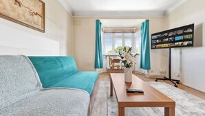 A living room with a sofa, a coffee table, a TV, and a window with curtains. - *Modern Spacious studio flat in Ealing* (Hangerlane )