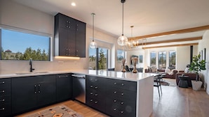 A modern kitchen with dark cabinets, a large island, and pendant lighting. - Walk to Town | Near Free Shuttle (Fraser)