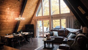 Un interior acogedor con comedor, un sofá de cuero y ventanas amplias que ofrecen vistas al exterior.