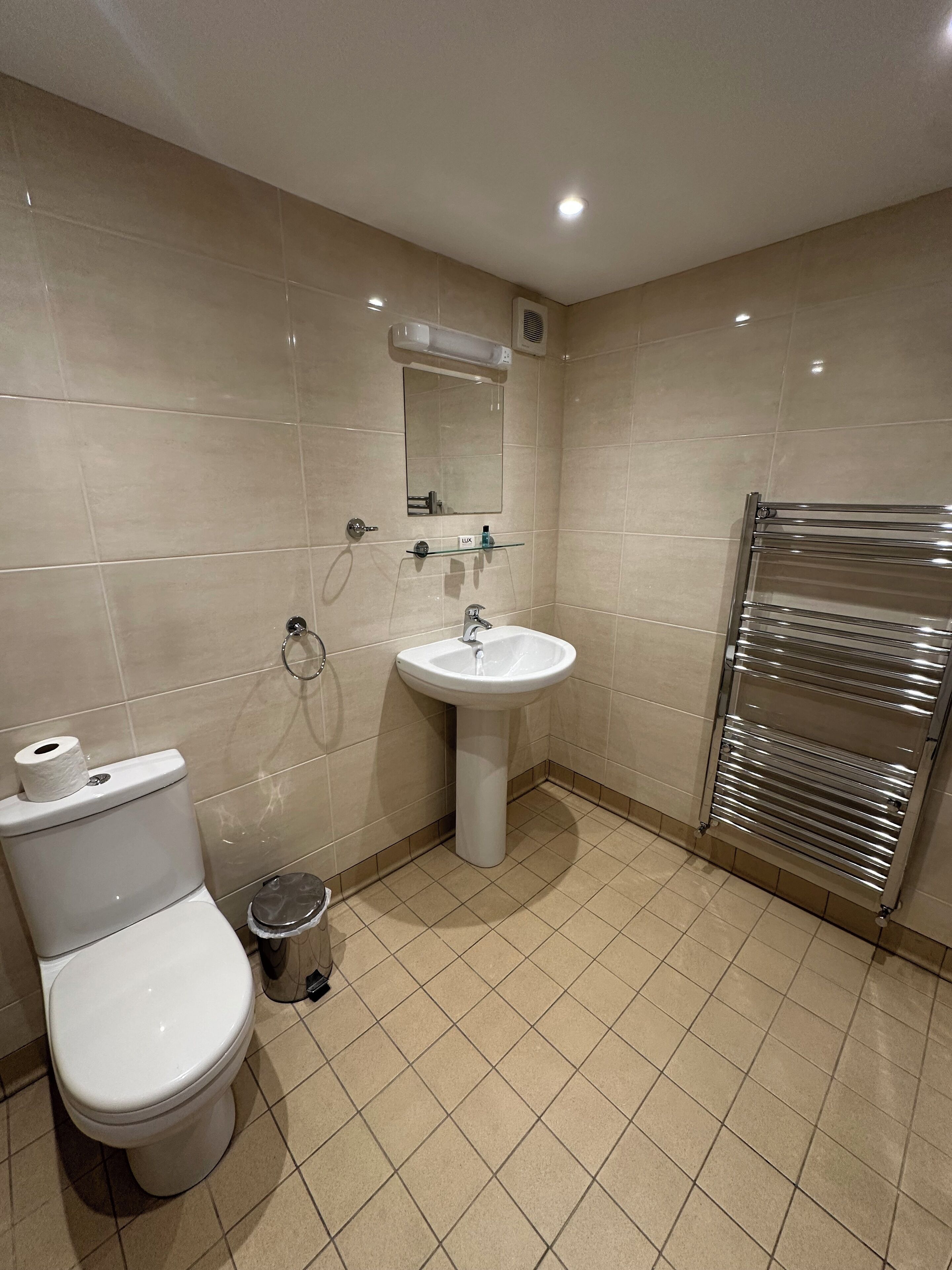A bathroom with a toilet, sink, mirror, and towel rack.