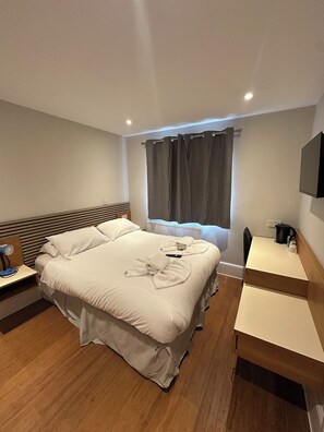 A hotel room with a large bed, bedside tables, a desk, and a TV. - Cavendish Hotel (High Wycombe)