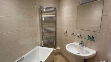 Un baño moderno con bañera, lavamanos y un perchero para toallas.
