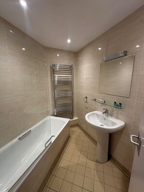 A modern bathroom with a bathtub, a sink, and a towel rack. - Cavendish Hotel (High Wycombe)