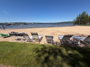 A beach with lounge chairs and a person in the water.