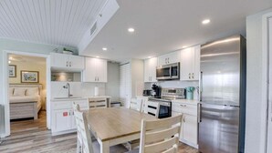 Una cocina moderna con armarios blancos, electrodomésticos de acero inoxidable y una mesa de comedor de madera.