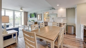 Una cocina moderna con armarios blancos, una mesa de comedor de madera y un televisor montado en la pared.