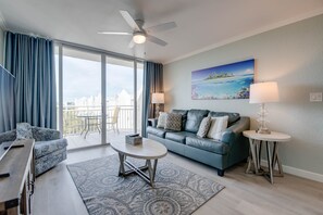 Un salon moderne avec un canapé, une table basse et un tableau représentant une scène de plage.