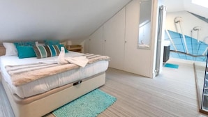 Ein Schlafzimmer mit einem Bett, einem Nachttisch, einem Spiegel und einer Treppe, die zu einer oberen Ebene führt.